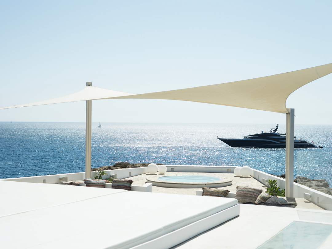 Beachfront terrace with yacht on the Mediterranean horizon